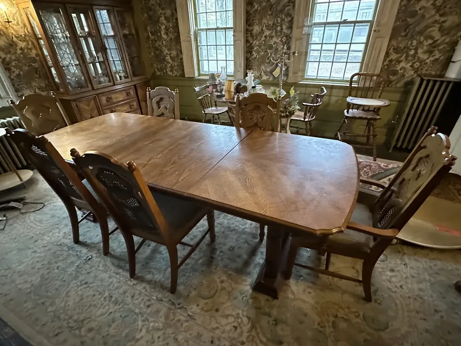 A dining room with table and chairs still set, a china cabinet visible in the background