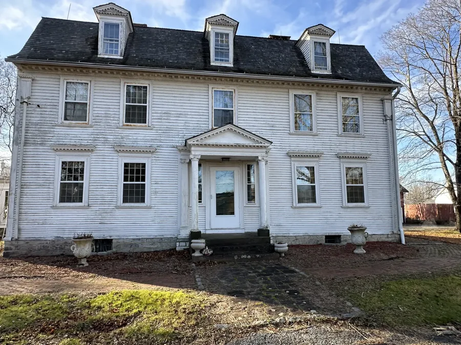 The front elevation before restoration began, with weathered clapboards and peeling paint on the entry portico