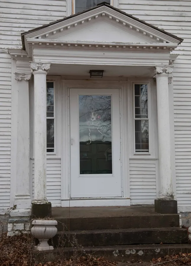 The front portico with its fluted Ionic columns and pediment, framing the entry door